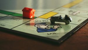 pexels-photo-1422673-1422673 Close-up shot of a Monopoly board game featuring a toy car and a red house on 'Go to Jail'.
